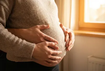 Gros plan chaleureux d'un ventre de grossesse avec des mains posées dessus.