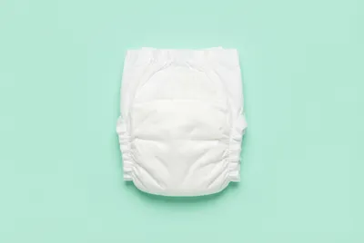 Vue minimaliste d'une couche blanche pliée centrée sur un fond vert menthe.