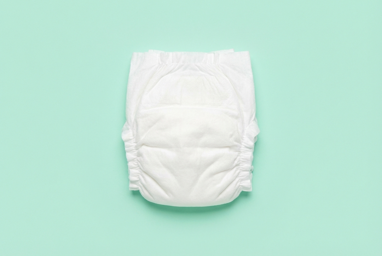 Quelle est la taille d'une couche pliée ? Dimensions types Vue minimaliste d'une couche blanche pliée centrée sur un fond vert menthe.